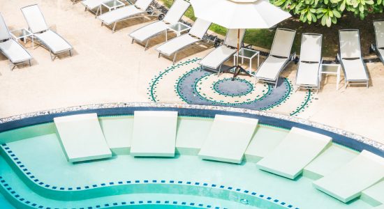 Outdoor swimming pool with umbrella and chair in hotel resort