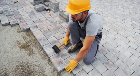 Concentrated at work. Man in yellow colored uniform have job with pavement.