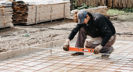 male worker measures the construction level of rebar for the foundation of a house under construction