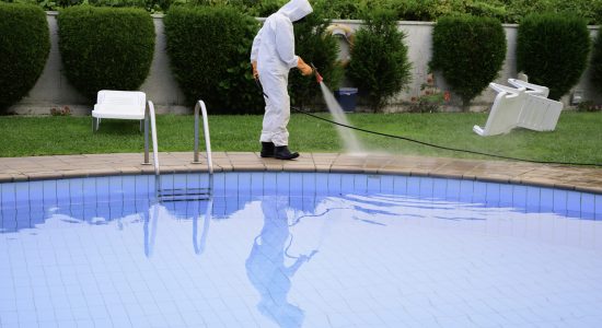 man with protection disinfects the pool floor by spraying with disinfectant product