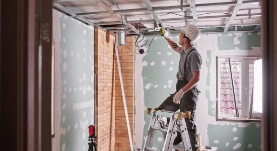 Room repair. Interior finish. young builder makes a plasterboard ceiling, standing on a stepladder
